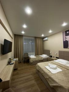 a hotel room with two beds and a flat screen tv at Silkway Deluxe 1 in Semey +14 photos