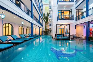 una piscina en un hotel con sillones azules en Silk River Hoi An Hotel & Spa, en Hoi An