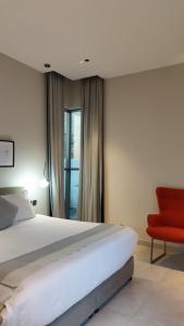 a bedroom with a bed and a red chair at شاليهات بلاسيو in Ḩayl