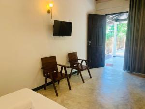 a room with two chairs and a table and a television at Wave Crest Villa in Dickwella