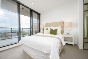 a bedroom with a white bed and a large window at Luxury Bay View Apartment in Melbourne