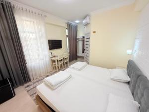 サマルカンドにあるSamarkand Travelの白いベッドルーム(ベッド2台、テーブル付)