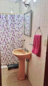 baño con lavabo y ducha con toalla rosa en LaCasitaBlanca, en Las Toninas