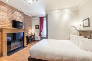 1 dormitorio con pared de ladrillo, cama y chimenea en Hotel Acadia, en Quebec