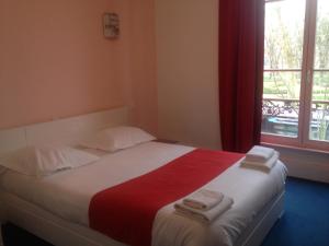 a bedroom with a large bed with towels on it at Hotel Couleurs Sud Centre-ville Gare Charleville-Mézières in Charleville-Mézières