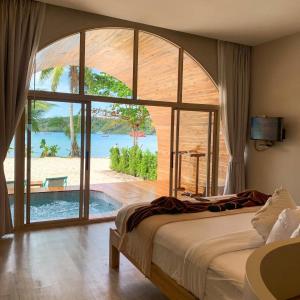 a bedroom with a large bed and a large window at Siam Beach Resort Koh Kood in Ko Kood