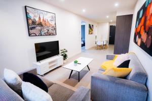a living room with a couch and a tv at Cozy Spacious Holiday 2B2B Melbourne CBD Apartment in Melbourne