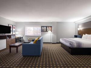 a hotel room with a bed and a couch and a tv at AmericInn by Wyndham Woodstock IL in Woodstock +26 photos