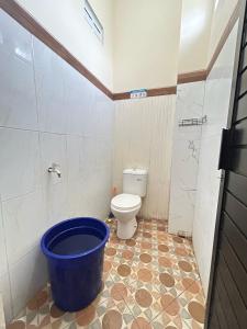 a bathroom with a toilet and a blue bucket at Rama Shinta Guesthouse & Coffee Yogyakarta in Yogyakarta