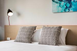 a bed with white pillows and pillows on top of it at Greenacre Hotel in Sydney