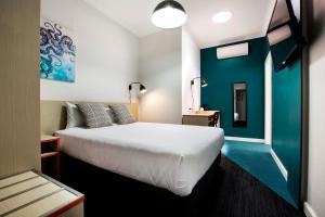 a bedroom with a white bed and a blue wall at Greenacre Hotel in Sydney