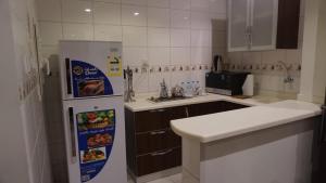 a kitchen with a white refrigerator and a sink at Awtad Elmasi Hotel in Mecca