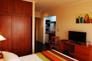 a bedroom with a bed and a desk with a television at Hotel Florencia Suites & Apartments in Antofagasta