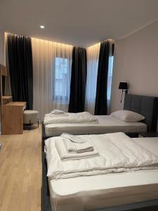 a hotel room with three beds in front of windows at Moaline Apartments, free parking in Sarajevo +155 photos