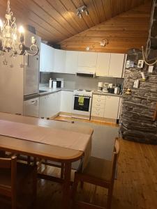 a kitchen with white cabinets and a wooden table at Villa Karhuntähti in Luosto