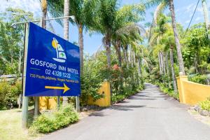 a sign for a school in a road with palm trees at Gosford Inn Motel in Gosford