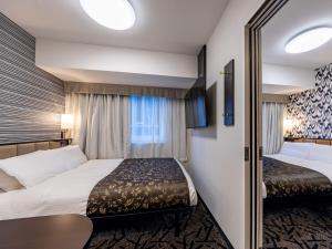 a hotel room with two beds and a window at APA Hotel & Resort Osaka Namba Ekimae Tower in Osaka