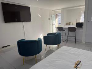 a living room with chairs and a flat screen tv at Humewood Gardens Private Suite in Gqeberha