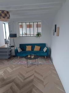 a living room with a blue couch and a table at La Maison de Juliette maison entière avec garage et terrain in Condé-sur-Sarthe