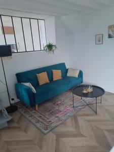 a living room with a blue couch and a table at La Maison de Juliette maison entière avec garage et terrain in Condé-sur-Sarthe +14 photos