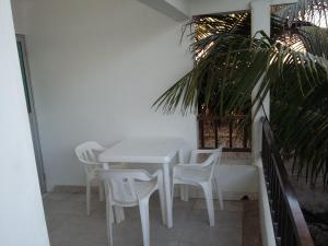 a white table and chairs on a patio with a palm tree at Hostal Poseidon del Mar in San Andrés