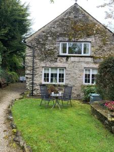 a stone house with a table and chairs in the yard at Willow View, Cartmel in Cartmel