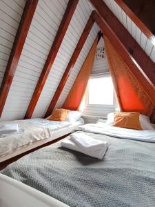 two beds in a attic room with a window at Białe Molo - Domki & SPA in Międzybrodzie Bialskie +93 photos