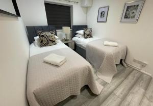 Cette chambre comprend 2 lits avec des couettes blanches. dans l'établissement Aisiki Living at Hayes, 3-Bedroom, Pet-Friendly House with Garden, Single or Double Beds, with Free Wi-Fi and Parking Space, à Northolt