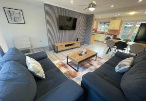 un salon avec un canapé bleu et une table dans l'établissement Aisiki Living at Hayes, 3-Bedroom, Pet-Friendly House with Garden, Single or Double Beds, with Free Wi-Fi and Parking Space, à Northolt