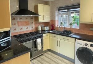 Il comprend une cuisine équipée d'une cuisinière. - un four à côté d'un lave-vaisselle dans l'établissement Aisiki Living at Hayes, 3-Bedroom, Pet-Friendly House with Garden, Single or Double Beds, with Free Wi-Fi and Parking Space, à Northolt