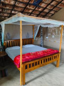 a wooden canopy bed with a red blanket on it at Shiva kashi Home stay in Maheshwar +30 photos