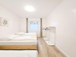 two beds in a white room with a window at Tolstov Apartments - 2 Room Apartment - 25 min Messe DUS in Duisburg