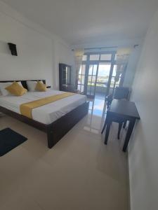a bedroom with a bed and a table and a desk at captain mirissa in Mirissa