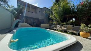 a swimming pool in a yard with chairs and a building at Pousada Sol de Imbassai in Imbassai