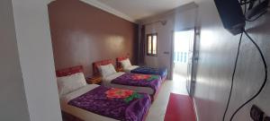 two beds in a room with purple sheets at Hotel Marwa in Tan-Tan Plage +32 photos