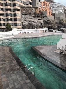 a swimming pool with green water in a city at Amejica - Apartment with terrace and sea view in Tabaiba