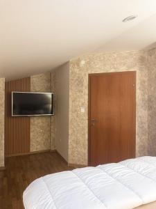 a bedroom with a bed and a television on a wall at Apartment Manastirska-Niksic in Nikšić