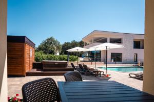 a patio with a table and chairs and a pool at VSG Resort - Relaxing Apartments, 200m from the Sea, with Pool, Sauna & Jacuzzi in Klimno