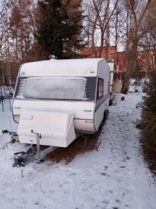 ロヴァニエミにあるOunasvaara Caravanの雪庭に置かれた白いトレーラー