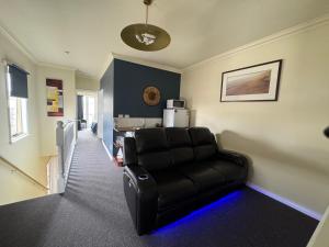 a living room with a black leather couch in a room at Banyan Place in Warrnambool