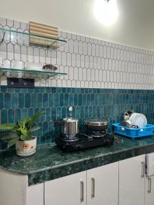 a kitchen counter with a stove and blue and white tiles at Choudhury's Stay in Helāpākari