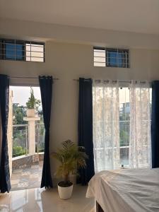 een slaapkamer met blauwe gordijnen en een groot raam bij Choudhury's Stay in Helāpākari