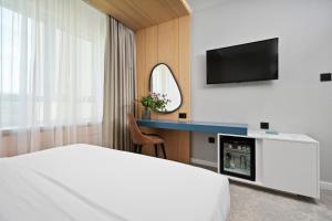 una camera d'albergo con letto e scrivania con TV di Nordic Resort a Novi Sad