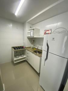 a white kitchen with a refrigerator and a sink at Loft central com garagem in Pelotas