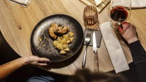 a person sitting at a table with a plate of food at Monaco Sport Hotel in Santo Stefano di Cadore