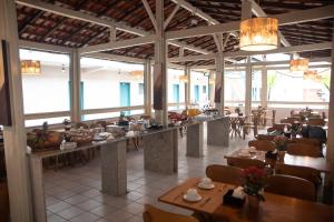 a dining room with tables and chairs and windows at Hotel Praia do Morro in Guarapari