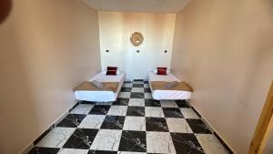 two beds in a room with a checkered floor at Soraya guest house surf camp & Restaurant in Imsouane +5 photos