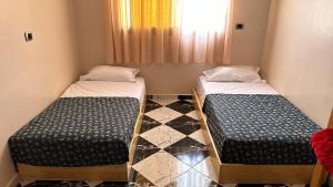 two beds in a small room with a window at Soraya guest house surf camp & Restaurant in Imsouane