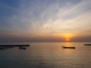 a group of boats in the water at sunset at Villa de la Plage sous les cocotiers in Saly Portudal