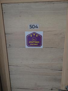 une porte en bois avec un panneau. dans l'établissement Sunčani breg resort&spa Kopaonik Studio Apartmani, à Kopaonik